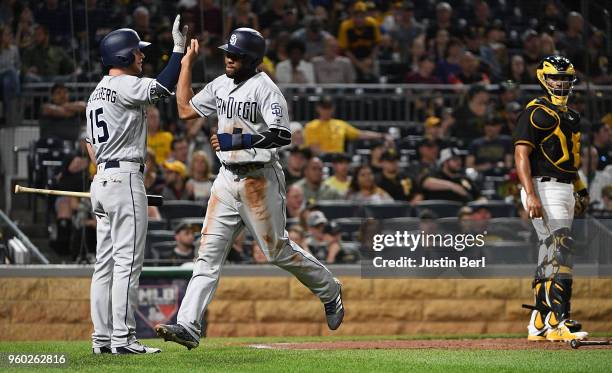 Elias Diaz of the Pittsburgh Pirates watches as Manuel Margot of the San Diego Padres high fives with Cory Spangenberg after coming around to score...