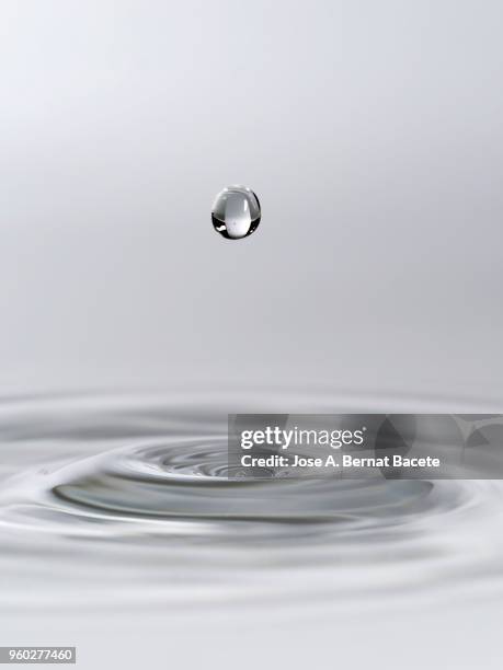 group of drops on line suspended in the air, falling down on a water surface that forms figures and abstract forms, on a white background. - sinus stockfoto's en -beelden