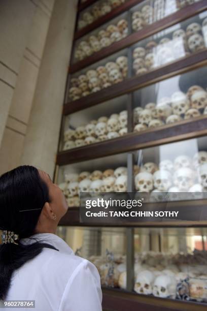 Woman looks at skulls at the Choeung Ek memorial in Phnom Penh on May 20, 2018. - Cambodians observed the annual 'Day of Anger' against genocidal...