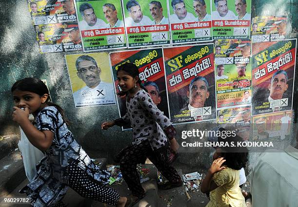 Sri Lankan children scamper past an election poster of former army general and presidential election contender Sarath Fonseka in Colombo on January...