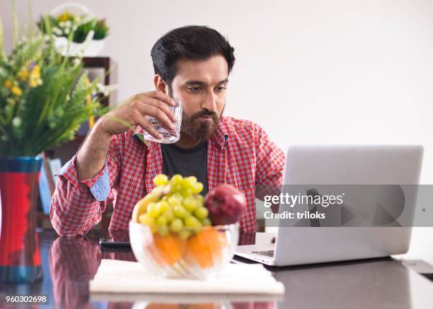 man drinking water while using laptop - apple laptop stock pictures, royalty-free photos & images