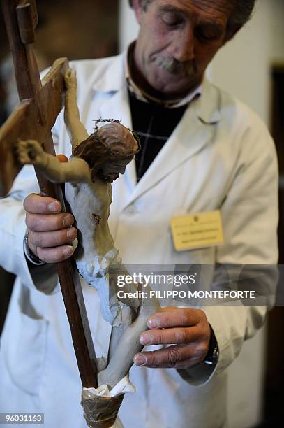 Anne-Sophie LEGGE An expert holds a broken statue of the Christ before its restoration in Celano, 50km from L'Aquila on January 14, 2010. Hundreds of...