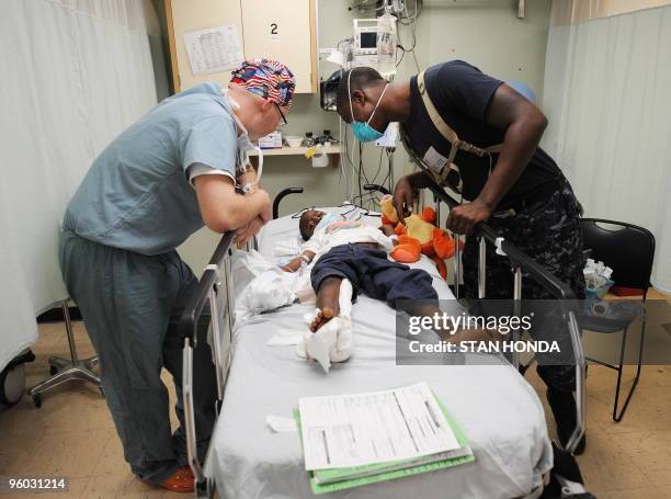 Doctor and interpreter speak to a young Hatian earthquake victim aboard the USNS Comfort hospital ship on 22 January, 2010 in the harbor off...