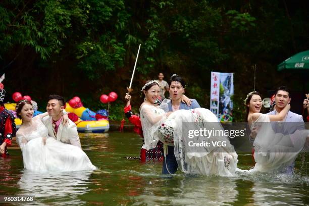 Staff members of Gulong Canyon Ecological Tourist Area with their mates participate in a group wedding at Gulong Canyon on May 19, 2018 in Qingyuan,...