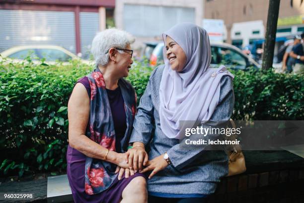 two malaysian women talking on the street of kuala lumpur - neighbours talking stock pictures, royalty-free photos & images