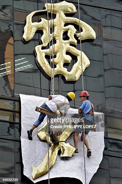 Workers intall new signs on a renovated building in Shanghai on August 19, 2009 at one of the many renovation sites that mushroomed in the city ahead...