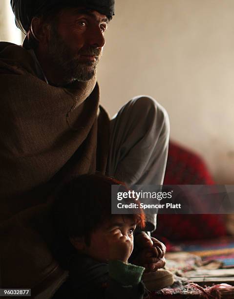 Man and his son listen as members of the US Army Able Company, 3-509 Infantry Battalion speak to residents of Zerak January 23, 2010 next to their...