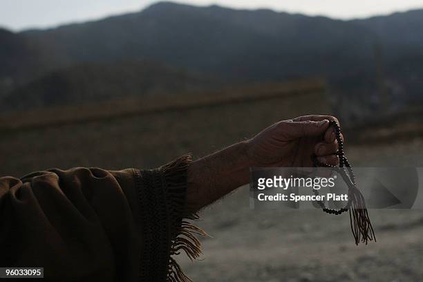 Man holds his prayer beads while being searched for weapons by a member of the Afghan National Police January 23, 2010 in Zerak, Afghanistan. Zerak,...