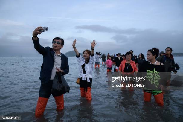 In a photo taken on May 18, 2018 people make their way out to sea during an annual extreme low tide event during the 'Jindo Sea Parting festival' in...
