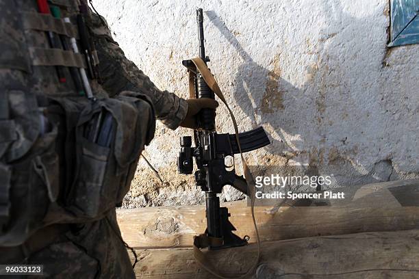 Soldier with the US Army Able Company, 3-509 Infantry Battalion grabs his weapon during a patrol along the main street of Zerak January 23, 2010 next...