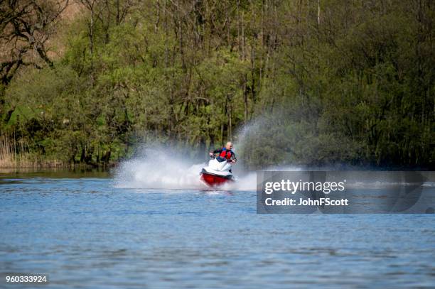 man on a jet ski on a scottish loch - johnfscott stock pictures, royalty-free photos & images