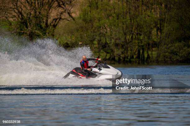 man on a jet ski on a scottish loch - johnfscott stock pictures, royalty-free photos & images