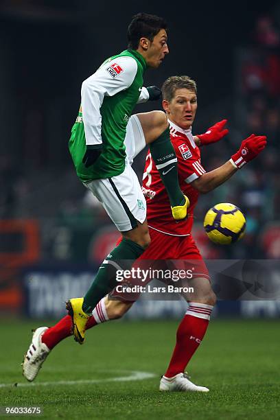 Mesut Oezil of Bremen is challenged by Bastian Schweinsteiger of Muenchen during the Bundesliga match between SV Werder Bremen and FC Bayern Muenchen...