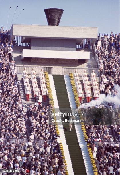 Yoshinori Sakai goes up steps in the national stadium to light torch, signifying opening of games.