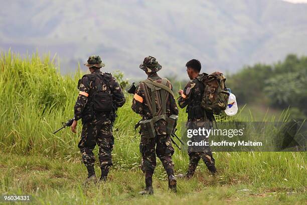 Soldiers patrol the area as family members, friends, supporters and peace advocates offer prayers at the site where 57 people, including journalists,...