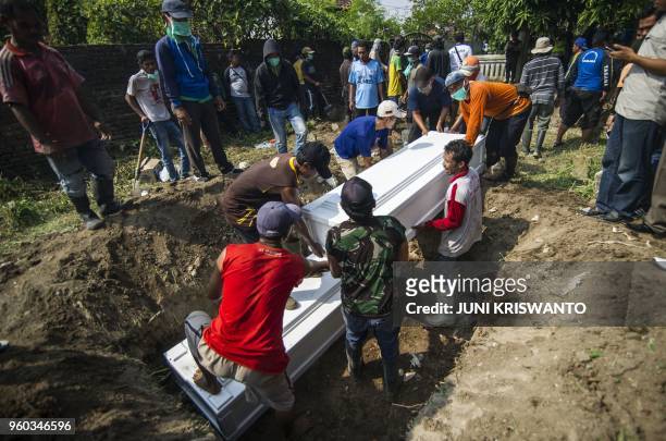 Indonesian men move coffins with the remains of suicide bombers during a burial in Sidoarjo, East Java on May 20, 2018. - Angry residents of an...