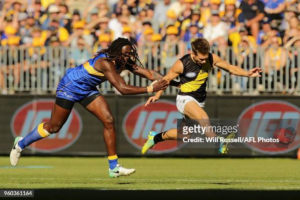 Dan Butler of the Tigers kicks the ball under pressure from Nic Naitanui of the Eagles during the round nine AFL match between the West Coast Eagles...