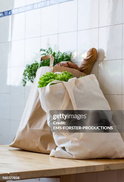 2 bags full of fresh healthy biological food in a kitchen on a table while bright day. - einkaufstüten stock-fotos und bilder