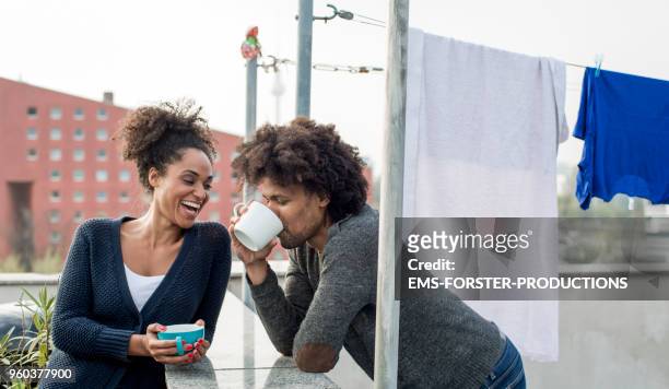 young mixed raced couple is drinking tea on roof top - neighbors stock-fotos und bilder