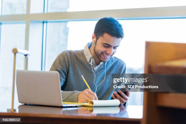 knappe college student maakt gebruik van technologie tijdens de studie - college application stockfoto's en -beelden