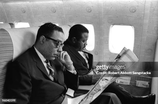 Civil rights activist the Reverend Ralph Abernathy , sitting next to the window, reads a newspaper while traveling with an unidentified Southern...