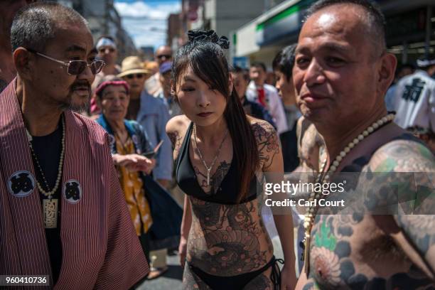 Heavily tattooed Japanese man and woman chat near Asakusa Temple during the third and final day of Sanja Festival, on May 20, 2018 in Tokyo, Japan....
