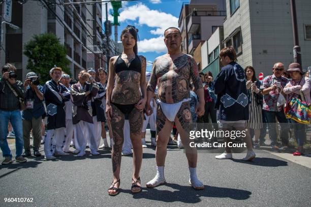 Heavily tattooed Japanese man and woman pose for photographs near Asakusa Temple during the third and final day of Sanja Festival, on May 20, 2018 in...