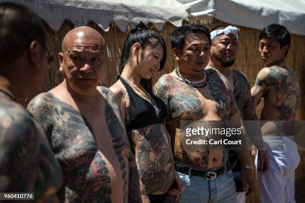 Heavily tattooed Japanese men and a woman pose for photographs near Asakusa Temple during the third and final day of Sanja Festival, on May 20, 2018...