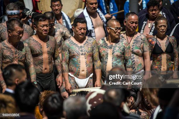 Heavily tattooed Japanese men and a woman pose for photographs near Asakusa Temple during the third and final day of Sanja Festival, on May 20, 2018...