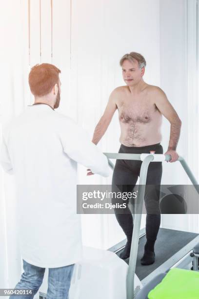 doctor helping mature patient walk after operation. - doctor's surgery stock pictures, royalty-free photos & images