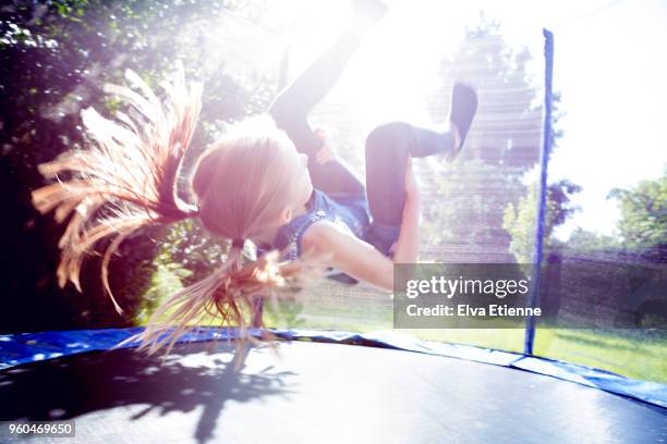 Girl (10-11) doing a somersault on a trampoline