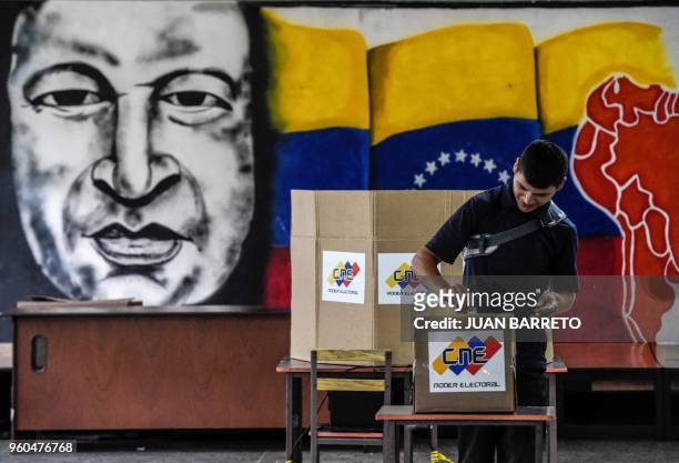 Man casts his vote in front of an image of late Venezuelan president Hugo Chavez, during the presidential elections at a polling station in Caracas...