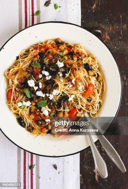 traditional italian food pasta spaghetti with red bell pepper, cherry tomatoes, eggplant or aubergine, salted feta cheese on a plate on a wooden table, top view. rustic style. vegetarian food option. - geroosterde rode paprika stockfoto's en -beelden