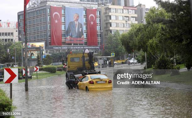 Man tries to remove a car stuck in a flooded street as torrential rains hit Ankara, on May 20, 2018.