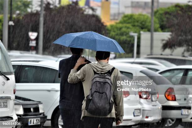 Two men walk with an umbrella outside a shopping mall during heavy rainfall in the spring season in Ankara, Turkey, on Sunday, May 20, 2018.