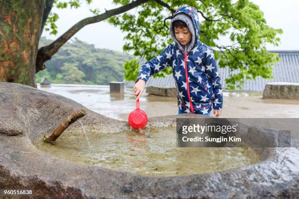 a boy is playing with mineral spring water at buddhist temple - sungjin kim stock pictures, royalty-free photos & images