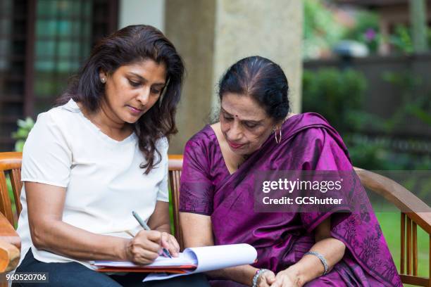 scheve in het papier als de dochter vult de laatste paar secties van het document. - indian mother and daughter stockfoto's en -beelden