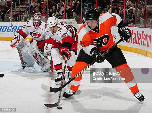 Danny Briere of the Philadelphia Flyers tries to skate around the defense of Tom Kostopoulos of the Carolina Hurricanes while goaltender Cam Ward...