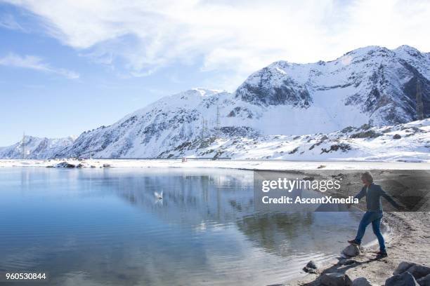 man skips stones in swiss alps lake - frozen water stock pictures, royalty-free photos & images
