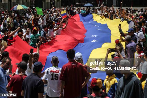 Venezuelans living in Medellin hold a national flag as they protest against Venezuelan President Nicolas Maduro and election being held in their...