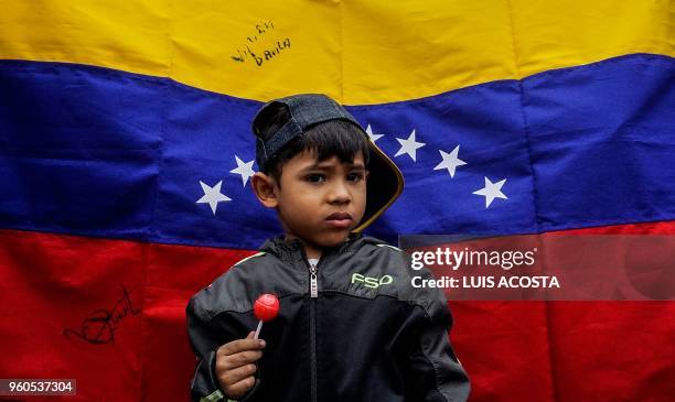 Boy stands in front of a Venezuelan national flag during a protest by Venezuelans living in Colombia against President Nicolas Maduro and the...