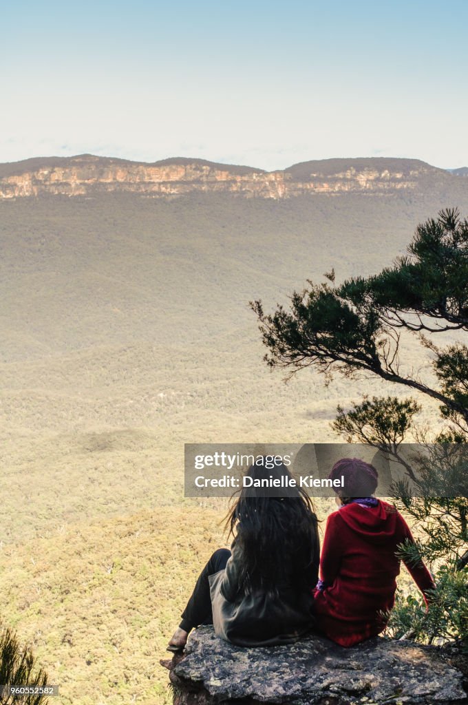 Two young women sitting on cliff