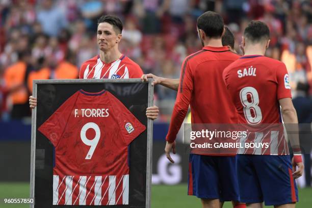 Atletico Madrid's Spanish forward Fernando Torres poses with a framed jersey signed by teammates at the end of the Spanish league football match...