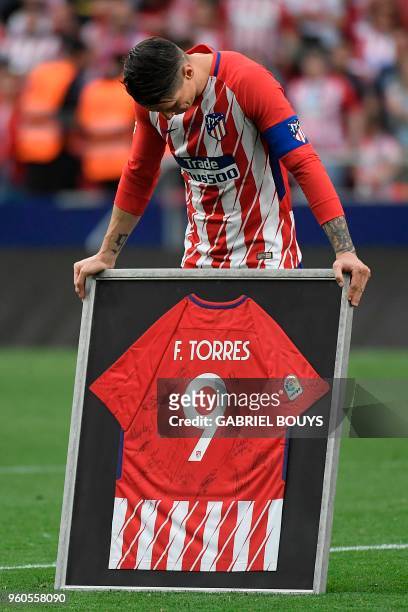 Atletico Madrid's Spanish forward Fernando Torres reacts as he receives a framed jersey signed by teammates during a tribute at the end of the...
