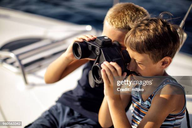 boys sitting on deck and using binoculars while sailing - miljko stock pictures, royalty-free photos & images