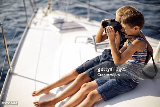 boys sitting on deck and using binoculars while sailing - miljko stock pictures, royalty-free photos & images