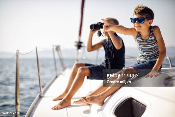 boys sitting on deck and using binoculars while sailing - miljko stock pictures, royalty-free photos & images