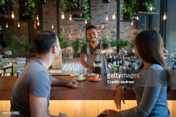 cameriere che serve caffè a una coppia in un bar - man eating at diner counter foto e immagini stock