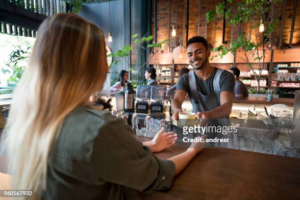 cameriere che serve caffè a una donna in un bar - man eating at diner counter foto e immagini stock