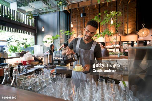 uomo che serve caffè in un bar - man eating at diner counter foto e immagini stock